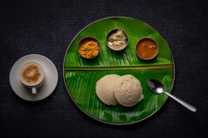 eine grüne Platte mit verschiedenen Arten von Speisen und einer Tasse Kaffee in der Unterkunft Sri Udupi Hotel in Thiruvananthapuram