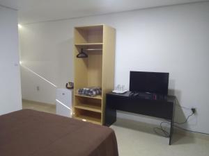Schlafzimmer mit einem Bett und einem Schreibtisch mit einem TV in der Unterkunft Hotel Boggiani in Asunción