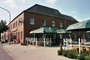 a building with tables and umbrellas in front of it at Hotel Hansen in Heinsberg