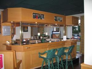 un bar avec quatre tabourets de bar verts dans un restaurant dans l'établissement Hotel Hansen, à Heinsberg