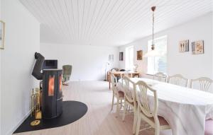 a dining room with a fireplace and a table and chairs at Nice Home In Randbl With Kitchen in Randbøl