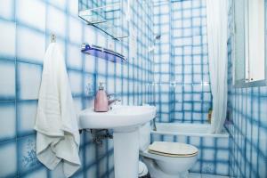 Un baño con azulejos azules, lavabo e inodoro. en Onefam Catedral, en Sevilla