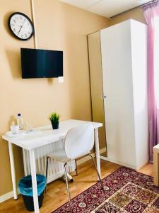 a white desk with a chair and a clock on the wall at Golden Hostel in Järfälla +8 photos