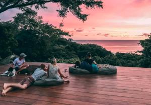a group of people sitting on top of a wooden deck at Buena Vista Surf Club in Playa Maderas