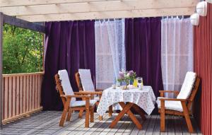 uma mesa e cadeiras num alpendre com cortinas roxas em 1 Bedroom Stunning Home In Grevie em Grevie