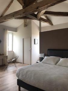 a bedroom with a large bed and a chair at La Clé du Puy in Cabariot