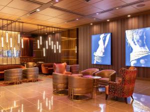 a lobby with tables and chairs and a large screen at SAHARA Las Vegas in Las Vegas