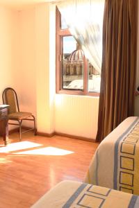 um quarto com uma cama, uma janela e uma cadeira em Hotel Maria Benita em Zacatecas