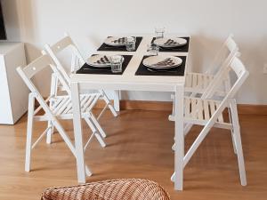 a white dining room table with four chairs and plates at Apartamento en Figueras, Asturias in Castropol
