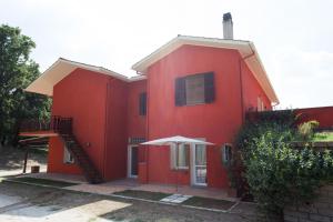 ein rotes Haus mit einem Regenschirm davor in der Unterkunft GUEST HOUSE IL LEONE in Viterbo