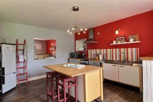 a kitchen with red walls and a wooden counter top at Holiday home Le Gite de Kerneuil in Gommenecʼh