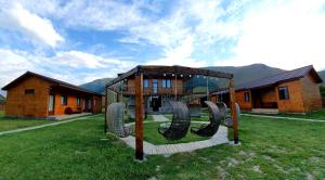 a playground in front of a house with mountains at Hotel Migu Yard in Stepantsminda