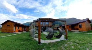 un parco giochi di fronte a una casa con montagne di Hotel Migu Yard a Kazbegi