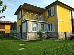 a yellow house with a balcony and a yard at Marconi 11 in Bardello