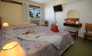 Un dormitorio con dos camas y un espejo. en Hotel Aconcagua, en San Carlos de Bariloche