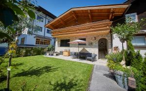 a patio with an umbrella and a lawn at Landhaus Eberharter in Saalbach Hinterglemm