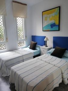 2 camas en una habitación con paredes y ventanas azules en Apartamento Puerto Banús, en Marbella