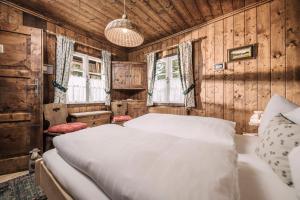 a bedroom with a bed and wooden walls and windows at Berghütte Hochpillberg in Pill
