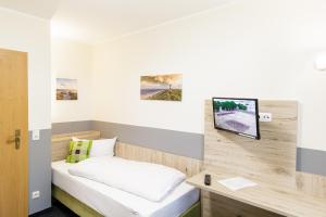 a room with a bed and a tv on a wall at Gästehaus Alexandra in Cuxhaven