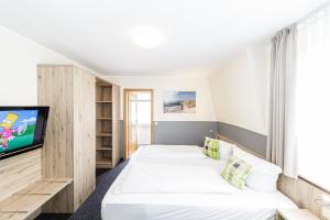a bedroom with two beds and a flat screen tv at Gästehaus Alexandra in Cuxhaven