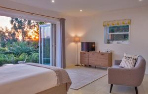 a bedroom with a bed and a chair and a window at Meadow Cottage Bed & Breakfast in Hawkhurst