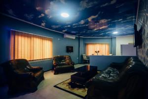 a living room with two leather chairs and a ceiling with a cloud mural at Guest House Royal Comfort With Terrace in Kutaisi