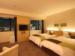 a hotel room with two beds and a flat screen tv at Hotel Keihan Kyobashi Grande in Osaka