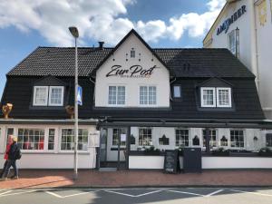 a woman walking in front of a inn post at Hotel Gasthof Zur Post in Cuxhaven