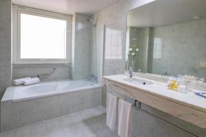 a bathroom with a tub, sink and mirror at Luna Esperanca Centro Hotel in Setúbal
