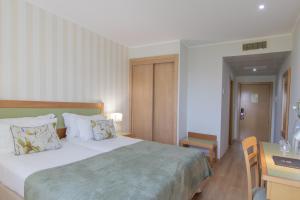 a bedroom with a bed, desk, chair and a lamp at Luna Esperanca Centro Hotel in Setúbal