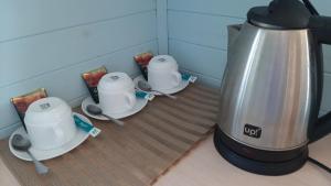 a coffee maker and three cups and saucers on a counter at Гостьовий дім на Герцена Guest hous on Gertsena in Novhorod-Siversʼkyy