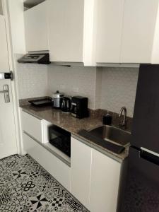 uma cozinha com armários brancos e um lavatório em Soderberg ( Near Airport | 50mbps Wifi | Netflix ) em Mactan