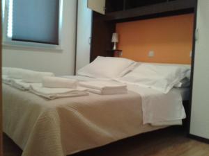 a bed with white sheets and folded towels on it at Sea view apartman Antonio in Zadar