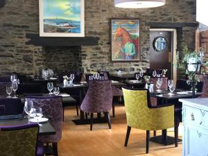 a restaurant with tables and chairs with purple chairs at Port Charlotte Hotel in Port Charlotte