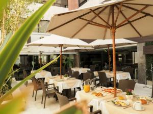 a restaurant with white tables and umbrellas at Hotel Marbella in Mexico City