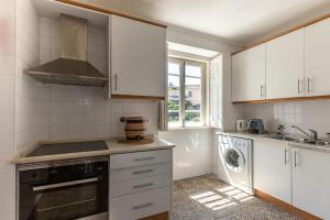 a kitchen with white cabinets and a sink and a dishwasher at Wine Inn Villa in Sintra