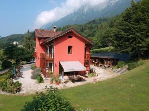 Villa Fiocco في Sospirolo: بيت احمر امامه طاوله وكراسي