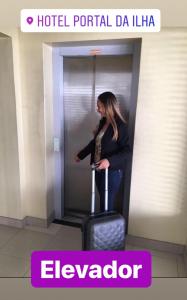 a woman standing in an elevator with a suitcase at Hotel Porthal da Ilha- Paulo Afonso-Ba in Paulo Afonso