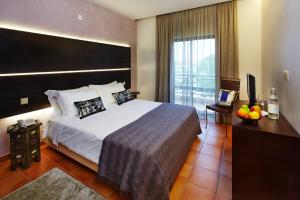 ヴィラモウラにあるHotel Parque das Laranjeirasの大きなベッドとバルコニーが備わるホテルルームです。