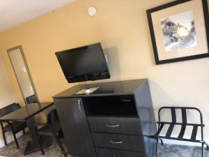 a room with a tv and a desk with chairs at Emerson Inn - Jacksonville in Jacksonville