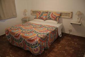 1 dormitorio con 1 cama grande con una manta colorida en La Chakana de Uribelarrea en Uribelarrea