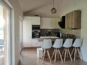 a kitchen with white cabinets and white stools at Kuldigas Holiday House in Kuldīga