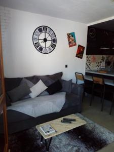 a living room with a couch and a clock on the wall at Le Plein Ciel in Bourg-Saint-Maurice