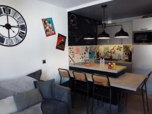 a kitchen with a table and a clock on the wall at Le Plein Ciel in Bourg-Saint-Maurice