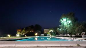 a swimming pool at night with chairs around it at Terre Di Vendicari in Noto