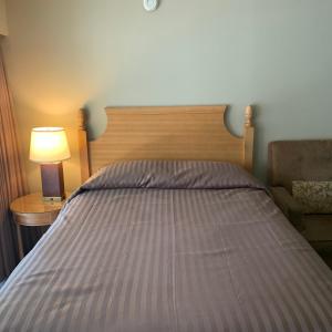 a bed with a wooden headboard and a lamp on a table at Okanagan Royal Park Inn by Elevate Rooms in Vernon