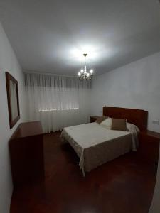 1 dormitorio con cama y lámpara de araña en ADUANA, en Ponteceso