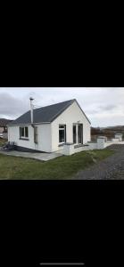 a white house with a black roof at The Chalet, 444 North Lochboisdale in Lochboisdale