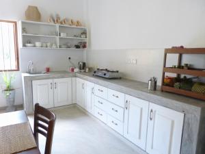 eine Küche mit weißen Schränken und einem Waschbecken und einem Tisch in der Unterkunft Sooriya Villa in Mirissa + 31 Fotos