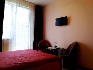 a bedroom with a bed and two chairs and a window at Viktoras Apartments in Palanga